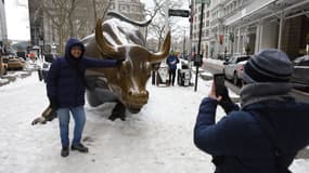 Un touriste pose devant la statue du taureau de Wall Street dans un froid extrême à New York, aux États-Unis, le 27 janvier 2026.
