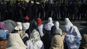 Des bouddhistes prient devant le temple de Dhammakaya dont l'accès est bloqué par des policiers, le 16 février 2017 au nord de Bangkok, en Thaïlande