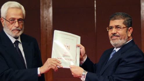 Mohamed Morsi (droite) recevant un exemplaire de son projet de Constitution.