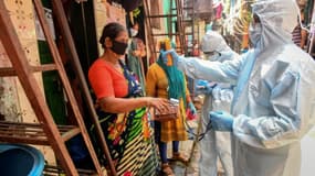 Des soignants en combinaison de protection font du porte-à-porte pour contrôler la température des habitants du bidonville de Dharavi, le 24 juin 2020 à Bombay, en Inde