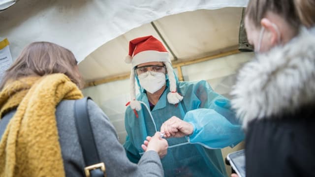 Un employé sanitaire avec un bonnet de Noël dans un centre de test de détection du Covid-19, le 23 décembre 2020 à Berlin, en Allemagne (PHOTO D'ILLUSTRATION).