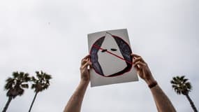 Une cagoule du Ku Klux Klan représenté sur une affichette lors d'une manifestation contre le suprémacisme blanc à Huntington Beach (États-Unis), le 11 avril 2021.