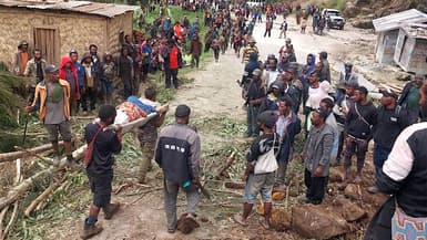 Des habitants transportant une personne sur une civière depuis le site d'un glissement de terrain dans le village de Yambali, dans la région de Maip Mulitaka, dans la province d'Enga en Papouasie-Nouvelle-Guinée, le 25 mai 2024.