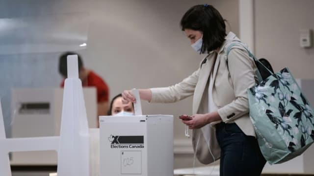 Une électrice glisse son bulletin dans l'urne pendant les élections législatives canadiennes, à Montréal, Québec, le 20 septembre 2021