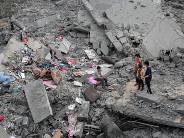 Des gens constatent la destruction d'une maison de la famille palestinienne al-Atrash, après avoir été détruite lors d'une frappe israélienne à Deir el-Balah, dans le centre de la bande de Gaza, le 13 mars 2024.