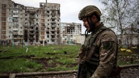 Un militaire ukrainien marche près d'un bâtiment résidentiel endommagé par des tirs d'obus dans la ville de Bakhmout, dans la région de Donetsk, le 23 avril 2023.