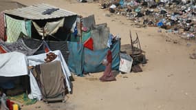 Une femme marche au milieu de tentes et de déchets dans une zone abritant des Palestiniens déplacés, à Khan Younès, dans le sud de la bande de Gaza, le 24 juillet 2024