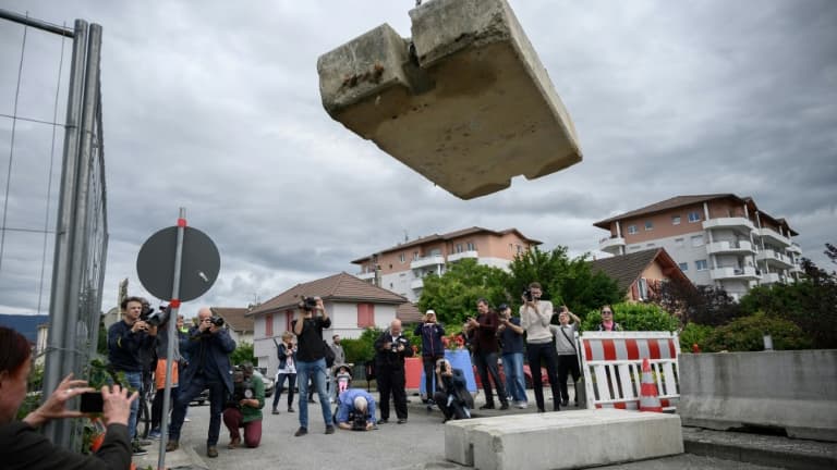 Journalistes et passants observent l'opération de retrait d'un bloc de béton qui fermait la frontière entre France et Suisse, le 14 juin 2020 à Thonex, en France Journalistes et passants observent l'opération de retrait d'un bloc de béton qui fermait la frontière entre France et Suisse, le 14 juin 2020 à Thonex, en France