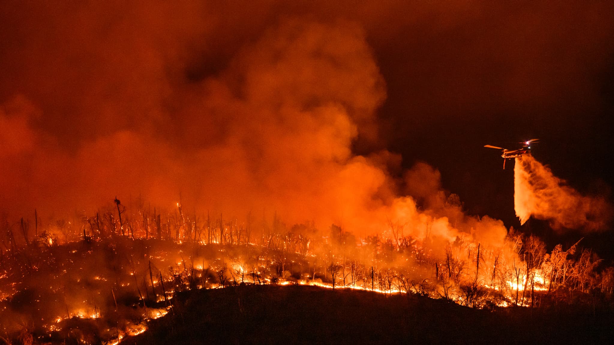 Un hélicoptère de nuit largue de l'eau sur l'incendie de forêt, à Oroville, en Californie, aux États-Unis, le 2 juillet 2024.