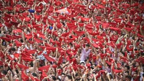 Des participants agitent leurs foulards rouges lors de la cérémonie d'ouverture du "Chupinazo" (fusée de départ) qui marque le coup d'envoi des fêtes taurines de la San Fermin devant la mairie de Pampelune, dans le nord de l'Espagne, le 6 juillet 2024.