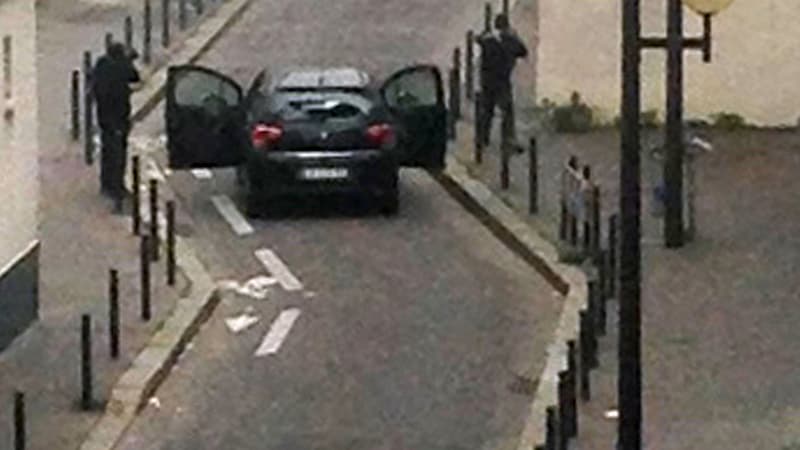 Les deux tireurs encagoulés, menacent une voiture de police après avoir attaqué Charlie Hebdo, ce mercredi matin.