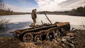 Un militaire ukrainien se tient près d'un tank russe détruit dans la ville de Trostyanets en Ukraine le 29 mars 2022