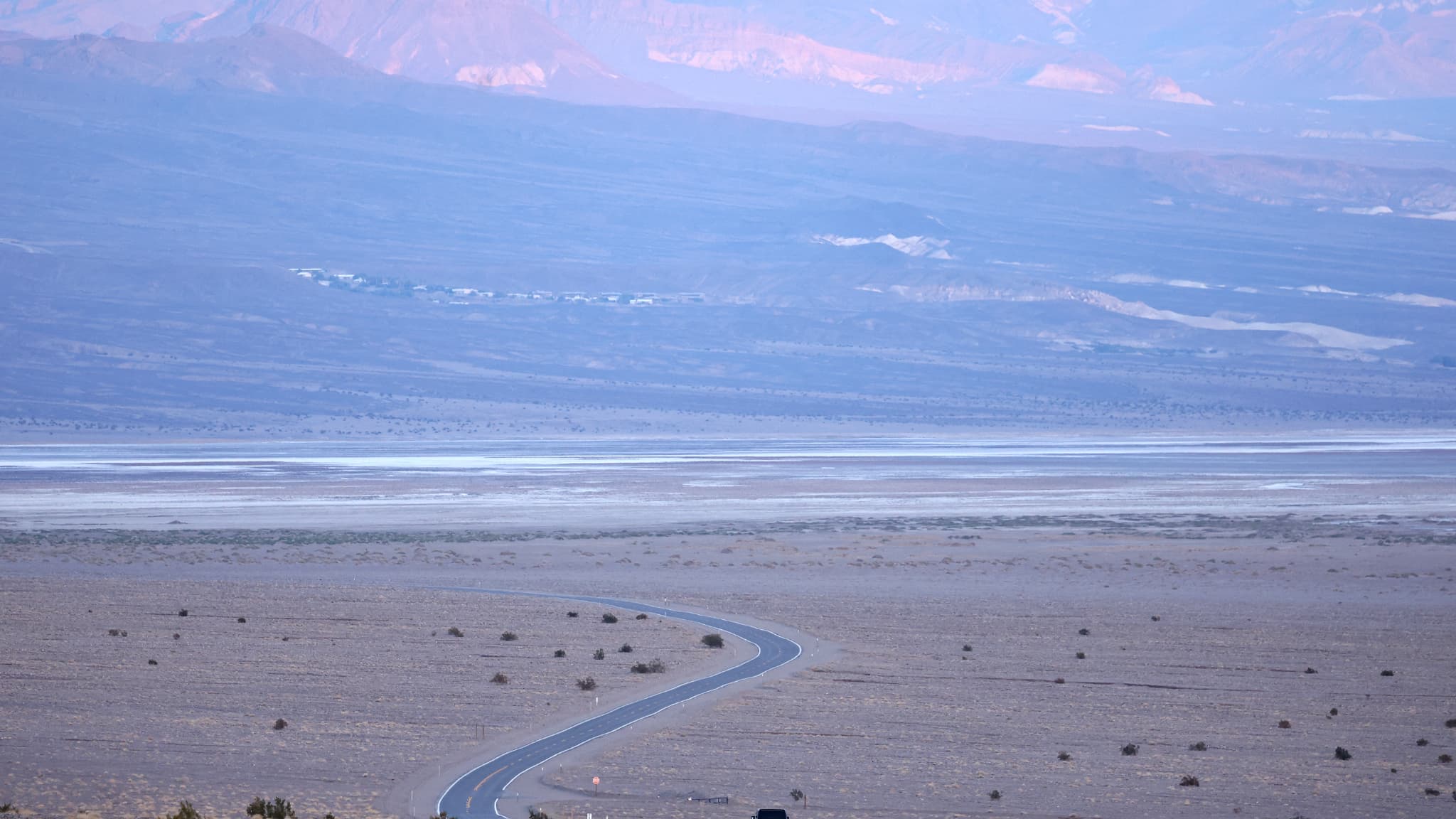  Un véhicule roule avant le coucher du soleil pendant une vague de chaleur de longue durée qui touche une grande partie de la Californie, le 8 juillet 2024, dans le parc national de la Vallée de la Mort, aux États-Unis.