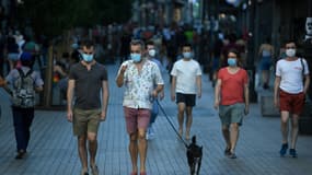 Des passants portant des masques obligatoires dans les lieux publics marchent dans le centre de Madrid le 30 juillet 2020 
