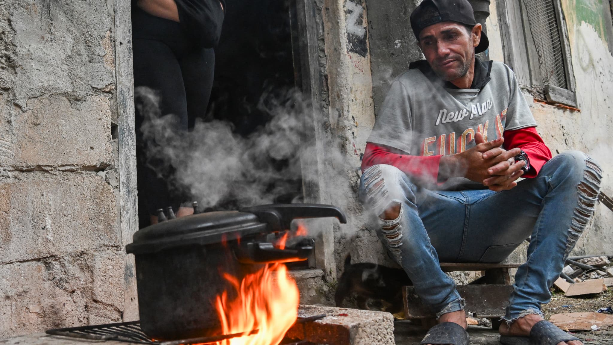 Un homme observe une casserole sur un feu de bois lors d'une panne de courant dans le quartier Poey de La Havane, le 28 janvier 2026.