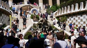 Des touristes visitent l'escalier monumental du parc Guell à Barcelone, le 13 avril 2024.