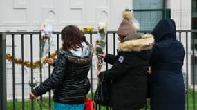 Des personnes déposent des fleurs devant l'appartement du rez-de-chaussée où les corps d'une femme et de ses quatre enfants ont été découverts, à Meaux, dans l'est de Paris, le 26 décembre 2023.