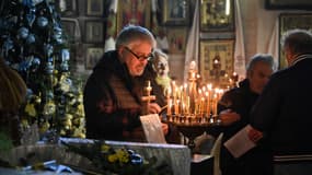 Un homme allume une bougie lors d'une messe de Noël orthodoxe à l'église Saint Jean le Théologien de Kharkiv, en Ukraine, le 24 décembre 2023.