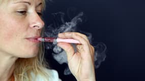 Une femme fume une cigarette électronique lors du salon Vapexpo, le 13 mars 2014.