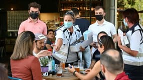Des médiateurs délivrent du gel hydroalcoolique à des consommateurs le 12 juin 202 à la terrasse d'un bar de Strasbourg après la découverte d'un cluster du variant delta du covid dans une école d'arts de la ville.