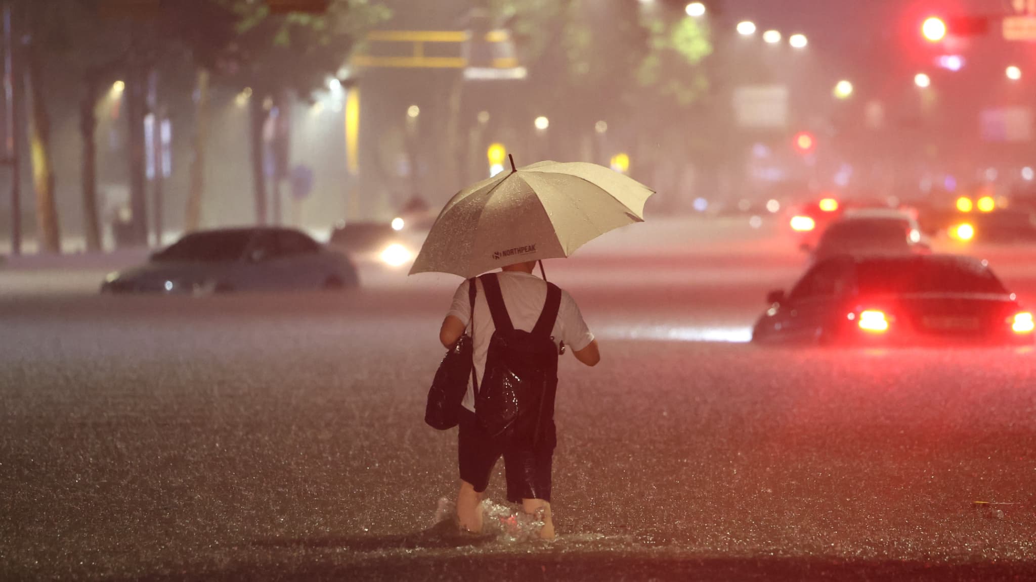 Un homme patauge dans une rue du quartier de Gangnam, à Séoul, durant les fortes intempéries du 8 août 2022