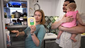 Maria Tyabut montre la nourriture stockée dans son nouveau réfrigérateur de fabrication chinoise tandis que son mari Sergei Duzhikov tient leur fille de 8 mois, Yekaterina, dans leur appartement de la banlieue moscovite de Mytishchi, le 17 juin 2025. Pour Sergei Duzhikov et Maria Tyabut, un couple de la classe moyenne vivant dans une ville juste à l'extérieur de Moscou, les sanctions occidentales contre la Russie à cause du conflit en Ukraine ont été gérables.