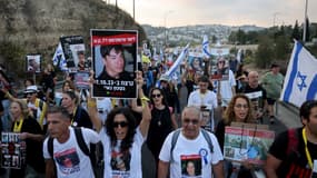 Des parents, des amis et des sympathisants des otages israéliens détenus dans la bande de Gaza depuis l'attaque du 7 octobre par des militants du Hamas dans le sud d'Israël, tiennent le drapeau israélien, des pancartes et des images de ceux qui ont été enlevés lors d'une manifestation appelant à leur libération, alors qu'ils marchent vers Jérusalem, le 17 novembre 2023.