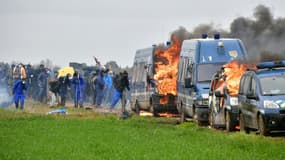 Des protestataires près de véhicules de gendarmerie incendiés lors d'affrontements entre forces de l'ordre et opposants à la construction de "bassines" de rétention d'eau, à Sainte-Soline dans les Deux-Sèvres, le 25 mars 2023