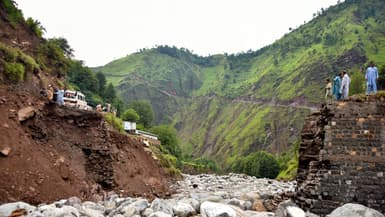 Des badauds se rassemblent près d'un pont détruit après des crues soudaines dans la banlieue de Muzaffarabad, la capitale du Cachemire sous administration pakistanaise, le 15 août 2025. 