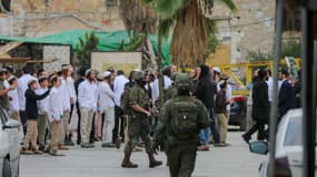 Les forces armées et des colons israéliens près de l'entrée de la vieille ville d'Hébron, en Cisjordanie occupée, le 6 décembre 2025. 