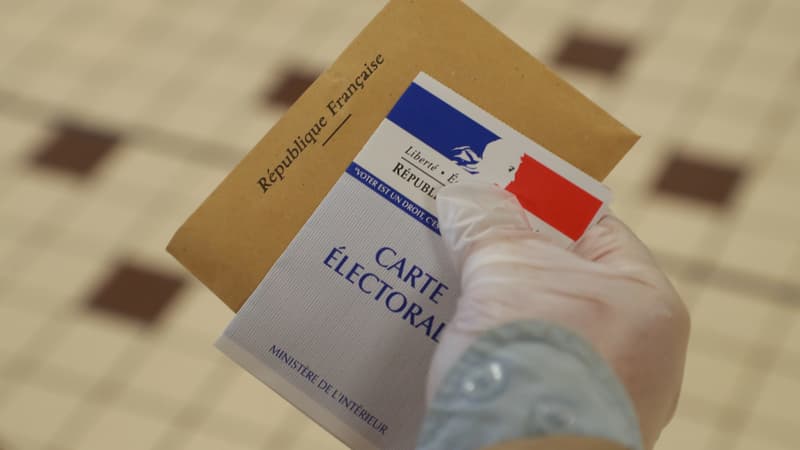 Une main gantée tient une carte électorale le 15 mars 2020, lors du premier tour des élections municipales, à Cucq.