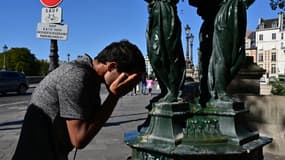 Un homme se rafraîchit le visage avec de l'eau d'une fontaine publique wallace à Paris, le 21 août 2023.
