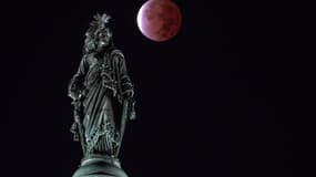 La Lune teintée de rouge, le 18 novembre 2021, au dessus de la statut de la Liberté située au sommet du Capitole, à Washington. 