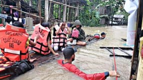 Les gardes-côtés philippins évacuent les habitants de maisons inondées par la tempête Megi, le 12 avril 2022 à Panitan, dans la province de Capiz
