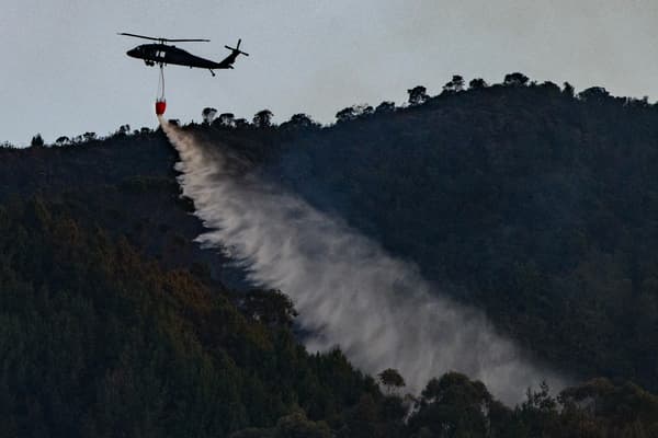 Un hélicoptère de la police colombienne largue de l'eau pour éteindre un feu de forêt à Bogota, le 24 janvier 2024. 