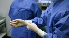 Un chirurgien enfile des gants avant d'opérer un patient, en novembre 2003 à Paris.