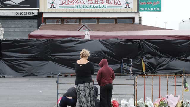 Des passants se recueillent devant la pizzeria où une voiture-bélier a foncé sur la vitrine, tuant une adolescente et blessant grièvement plusieurs personnes.