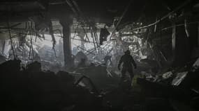 Un secouriste ukrainien inspecte les débris dans un centre commercial bombardé par l'armée russe, à Kiev le 21 mars 2022