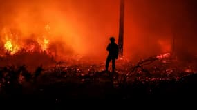 Un pompier se tient face aux flammes près du village de Belin-Béliet (Gironde) le 11 août 2022.