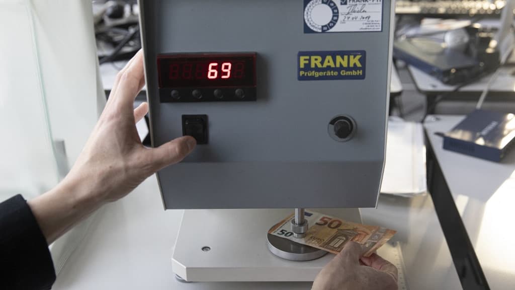 Une machine vérifie l'épaisseur d'un billet. Une machine vérifie l'épaisseur d'un billet.