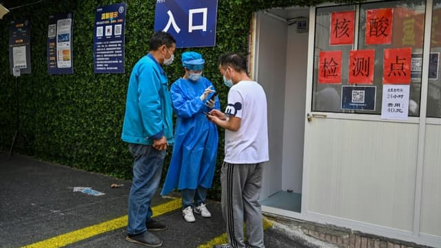 Un travailleur sanitaire aide des habitants de Shanghai à obtenir un QR code leur permettant de se faire dépister contre le Covid-19, le 14 mars 2022