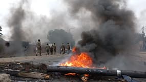 Des piétons passent devant une barricade en feu à Maputo (Mozambique), le 24 décembre 2024.