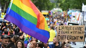 Des participants à la Marche des fiertés à Paris bradissent le drapeau arc en ciel et des pancartes, le 25 juin 2022