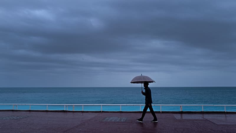 Un passant s'abrite de la pluie sous un parapluie, le long de la plage sur la "Promenade des Anglais" à Nice, le 30 octobre 2023. Photo d'illustration