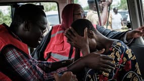 Un membre de la Croix-Rouge kenyane avec un adepte de l'église Good News International Church, soupçonnée de pratiquer la famine de masse, à Shakahola, le 25 avril 2023.