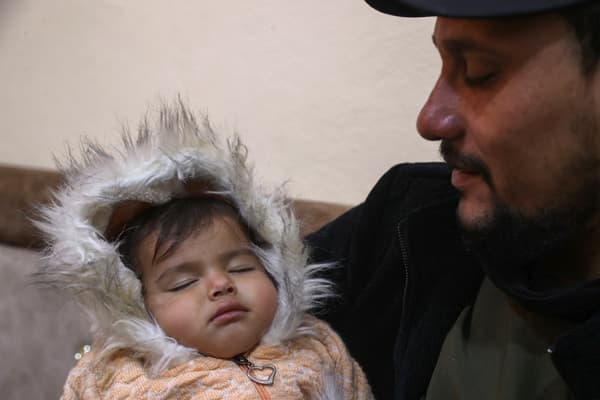 Khalil al-Sawadi avec sa nièce Afraa, sauvée des décombres du tremblement de terre, dans sa maison de la ville de Jandaris, dans le nord-ouest de la province d'Alep, le 2 février 2024.