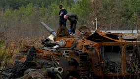 Un père et son fils examinent un tank russe détruit dans le village de Dmytrivka, près de Kiev, le 24 avril 2022