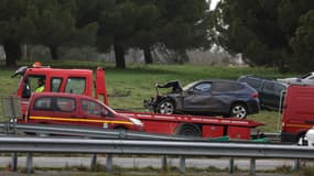 Un camion à plateau enlève le véhicule endommagé qui a tué une femme et grièvement blessé son mari et sa fille adolescente lorsqu'ils ont été écrasés à l'aube du 23 janvier 2024 à un barrage routier d'agriculteurs à Pamiers, dans l'Ariège, en France. 