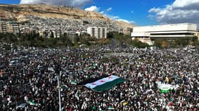 Des Syriens brandissent un drapeau à trois étoiles, utilisé par l'opposition depuis le début du soulèvement en 2011, alors qu'ils célèbrent la chute du régime de Bachar el-Assad sur la place des Omeyyades à Damas, le 13 décembre 2024. 