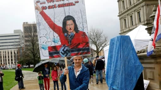 Un manifestant brandit une pancarte montrant la gouverneure du Michigan, Gretchen Whitmer, sous les traits de Adolf Hitler, lors d'une manifestation contre le confinement, le 30 avril 2020 à Lansing

pril 30, 2020